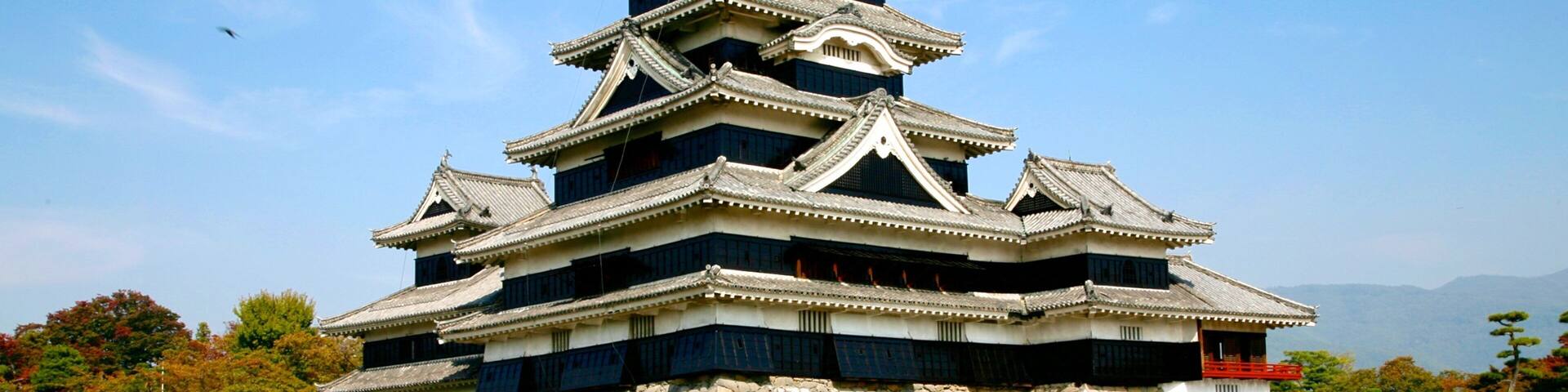 A traditional Japanese castle with multiple tiers, a stone base, and a surrounding moat.