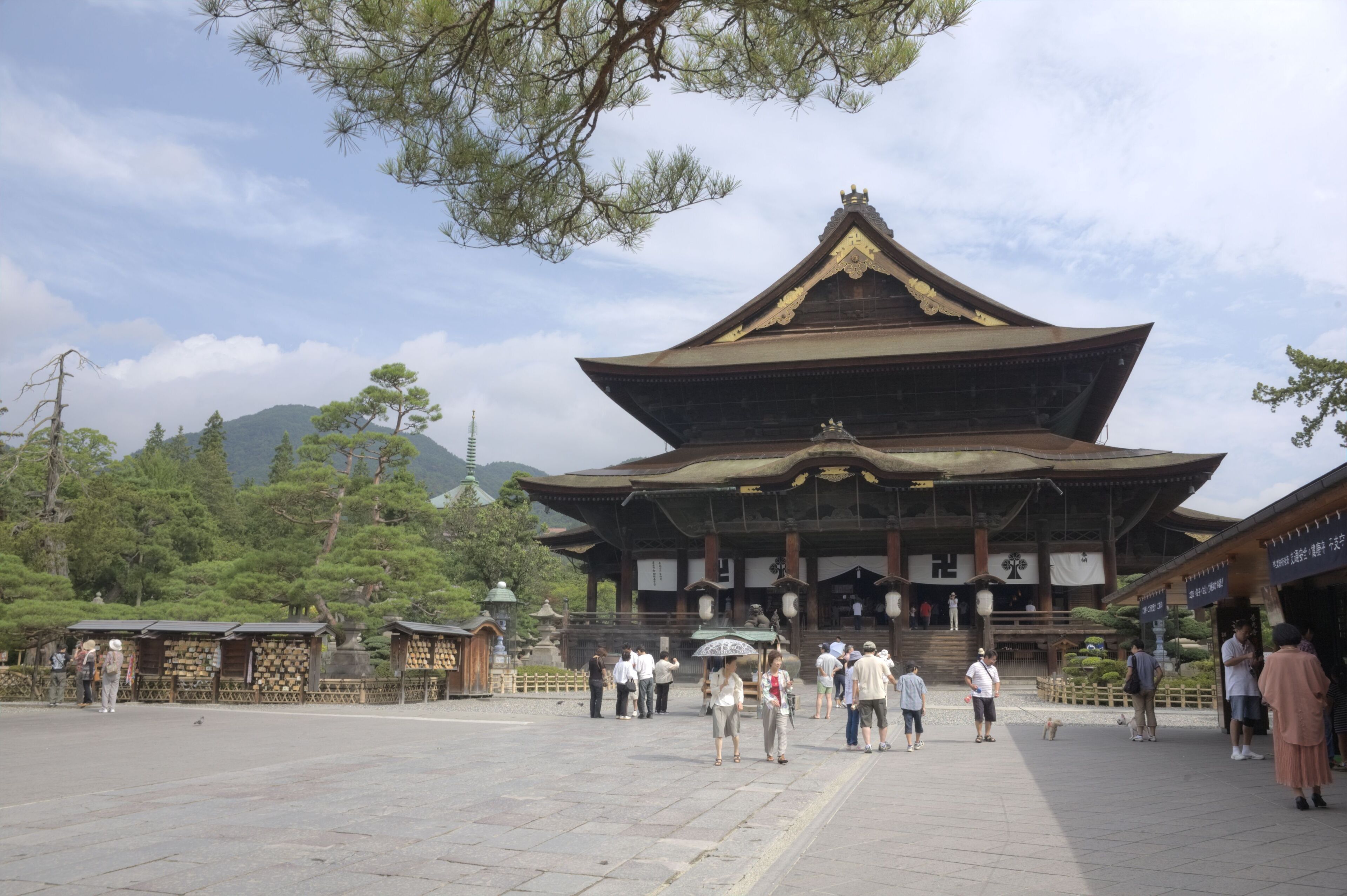 A traditional Japanese temple with a large, ornate roof and a stone courtyard.