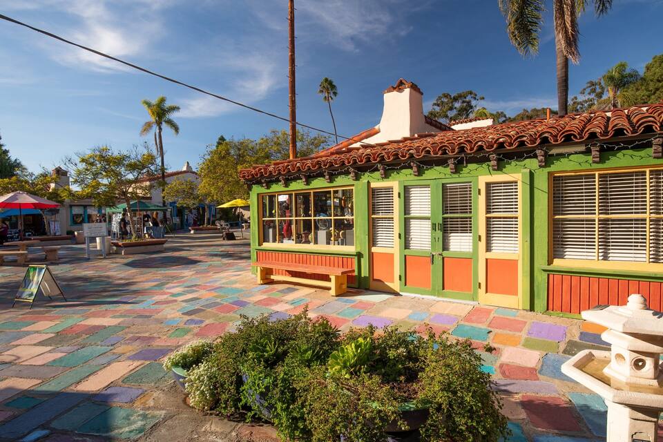 Un patio colorido con suelo de baldosas, un banco y una fuente.