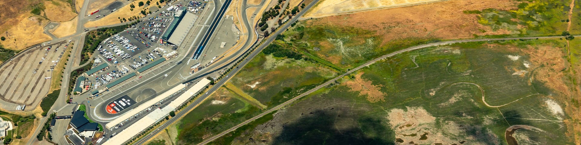 Aerial view of Sonoma Raceway in the golden grass fields and vinyards of wine country