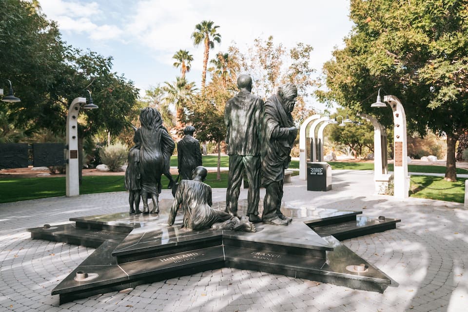 A bronze statue of a man and woman with a child in a park.