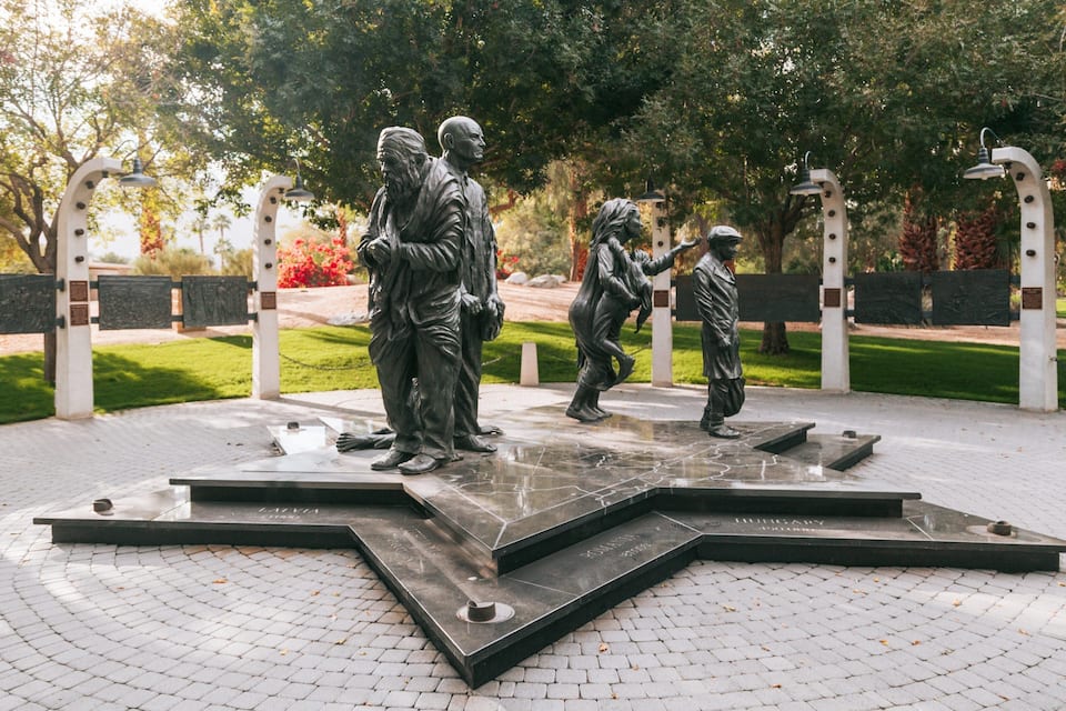 Eine Bronzestatue von drei Personen in einem Park.