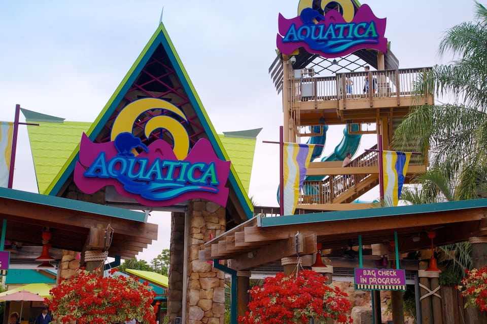 The entrance to Aquatica with colorful signage and a water slide.