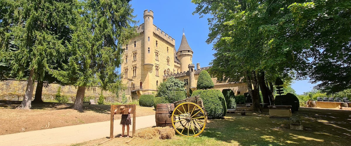A castle with a tower, surrounded by trees and a wooden cart.