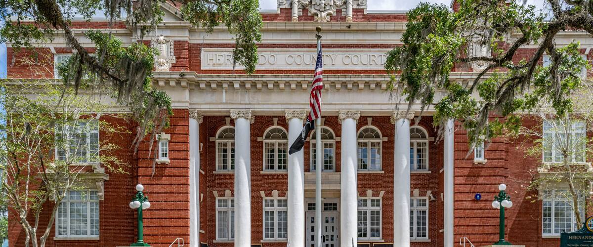 A red brick courthouse with white columns and steps leading up to the entrance.