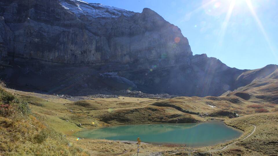 A mountainous landscape with a turquoise lake and a winding path.