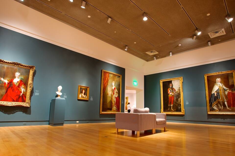 An art gallery with classical paintings and busts on display.