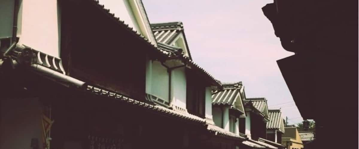 A traditional street with buildings featuring tiled roofs and wooden structures.