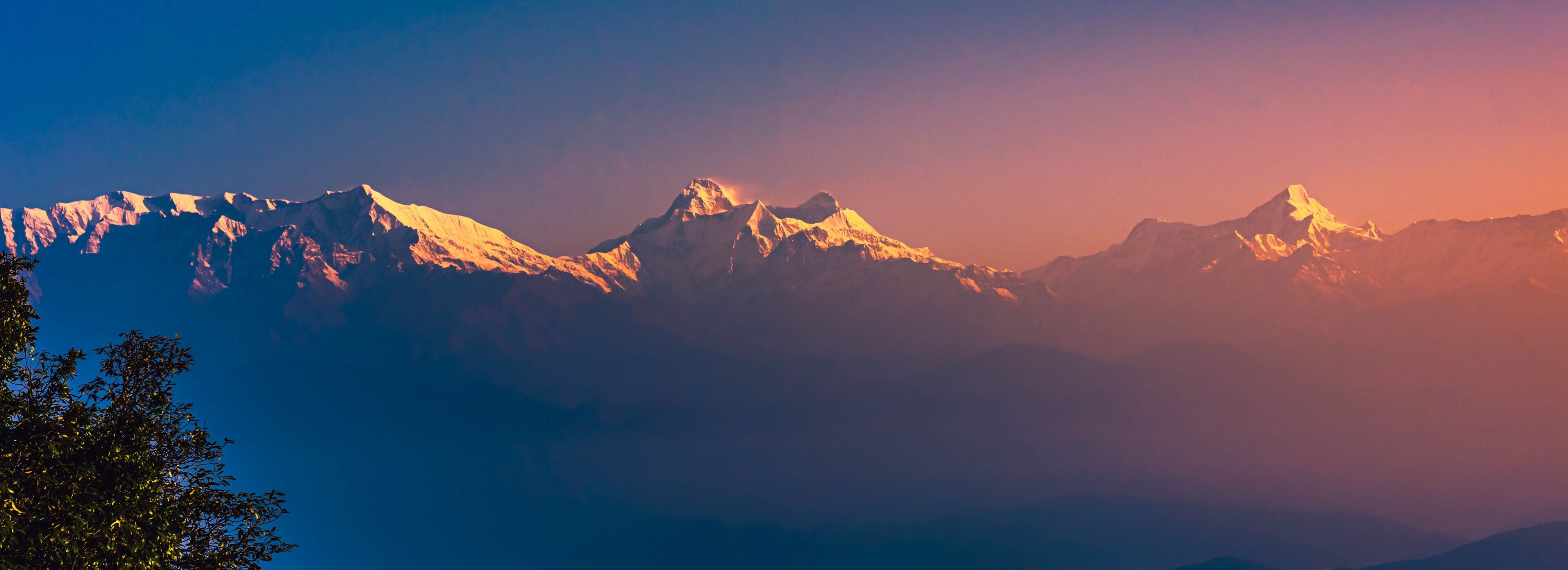 View of Himalayas mountain range with visible silhouettes through the colorful fog at Binsar, a hill station in Almora district, Uttarakhand, India.