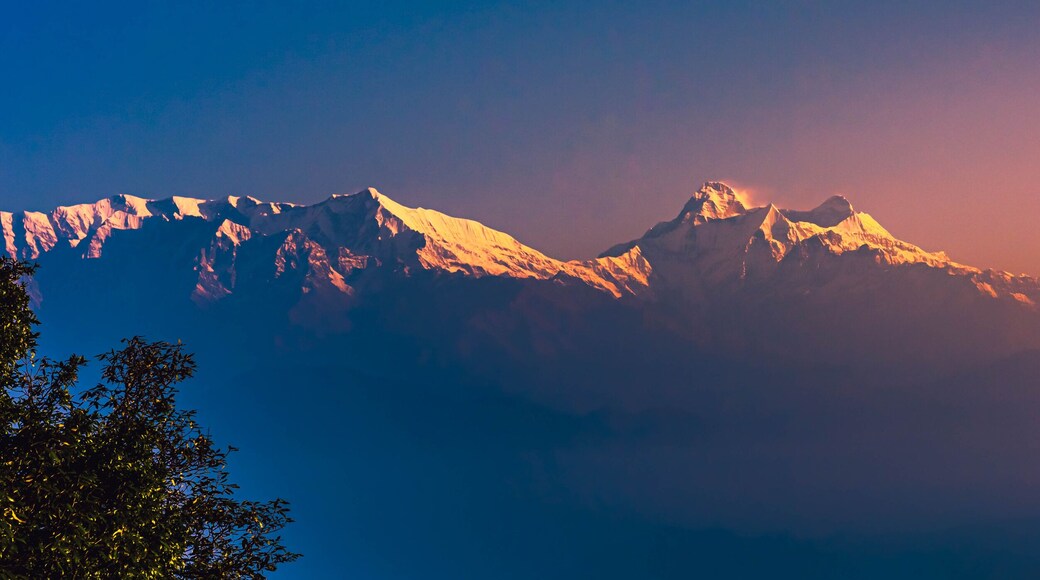 View of Himalayas mountain range with visible silhouettes through the colorful fog at Binsar, a hill station in Almora district, Uttarakhand, India.