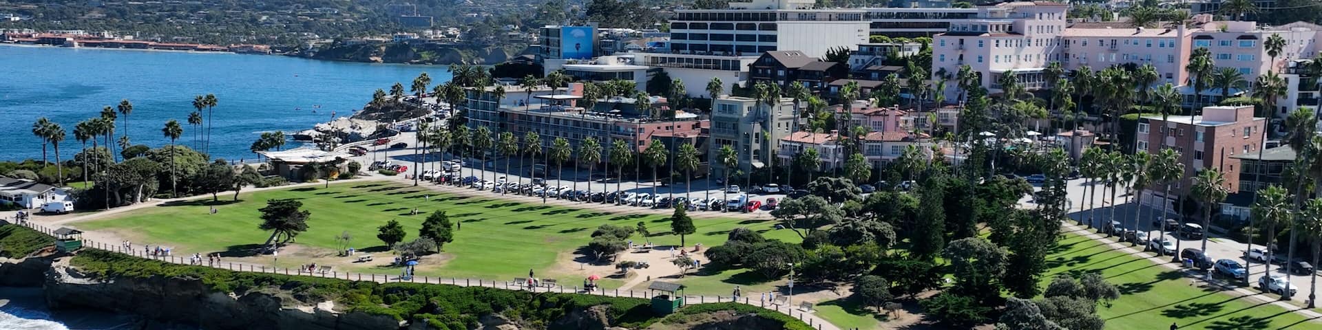 A coastal cityscape with a golf course, beachfront, and residential buildings.