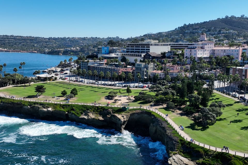 A coastal cityscape with a golf course, beachfront, and residential buildings.