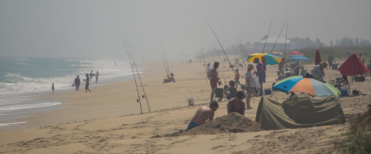 A beach with people fishing and tents set up.