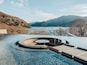 A circular pool with a view of a lake and mountains in the background.