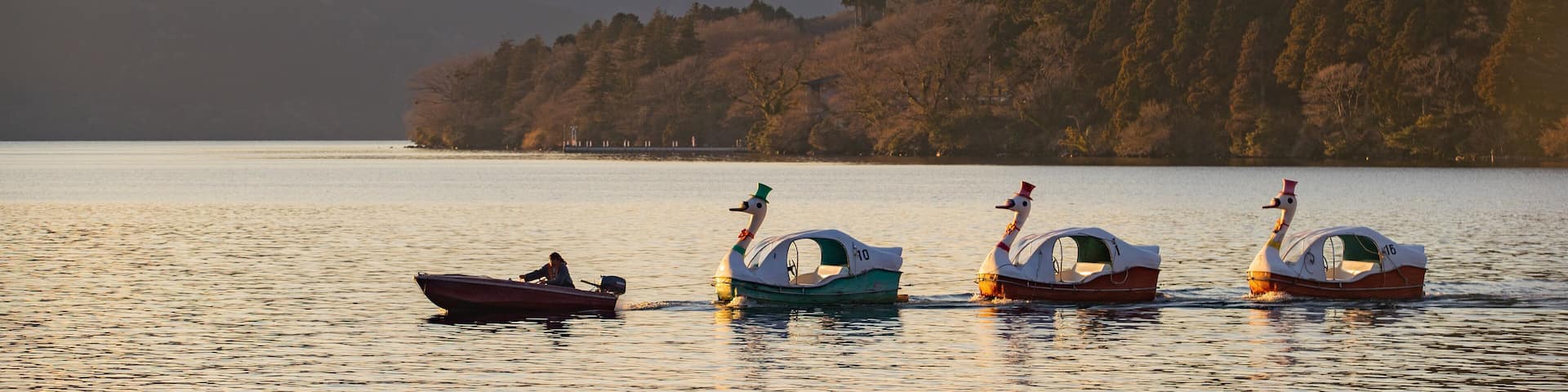 Three boats on a calm lake with a mountain in the background.