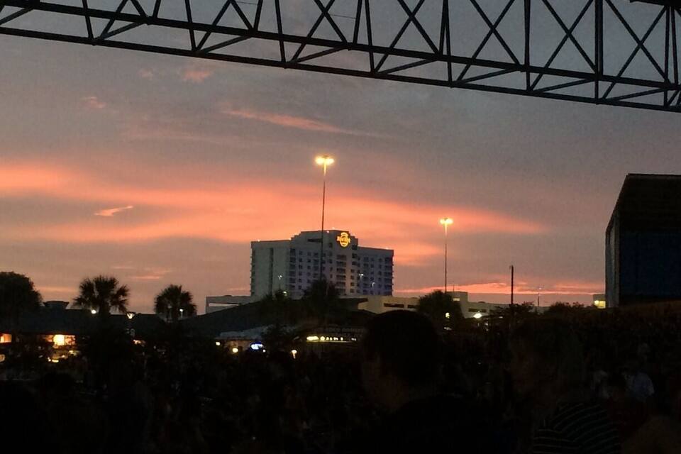 A sunset over a cityscape with a prominent hotel and a bridge structure.