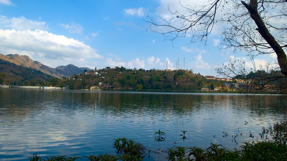 A calm lake with reflections of the sky and surrounding hills.