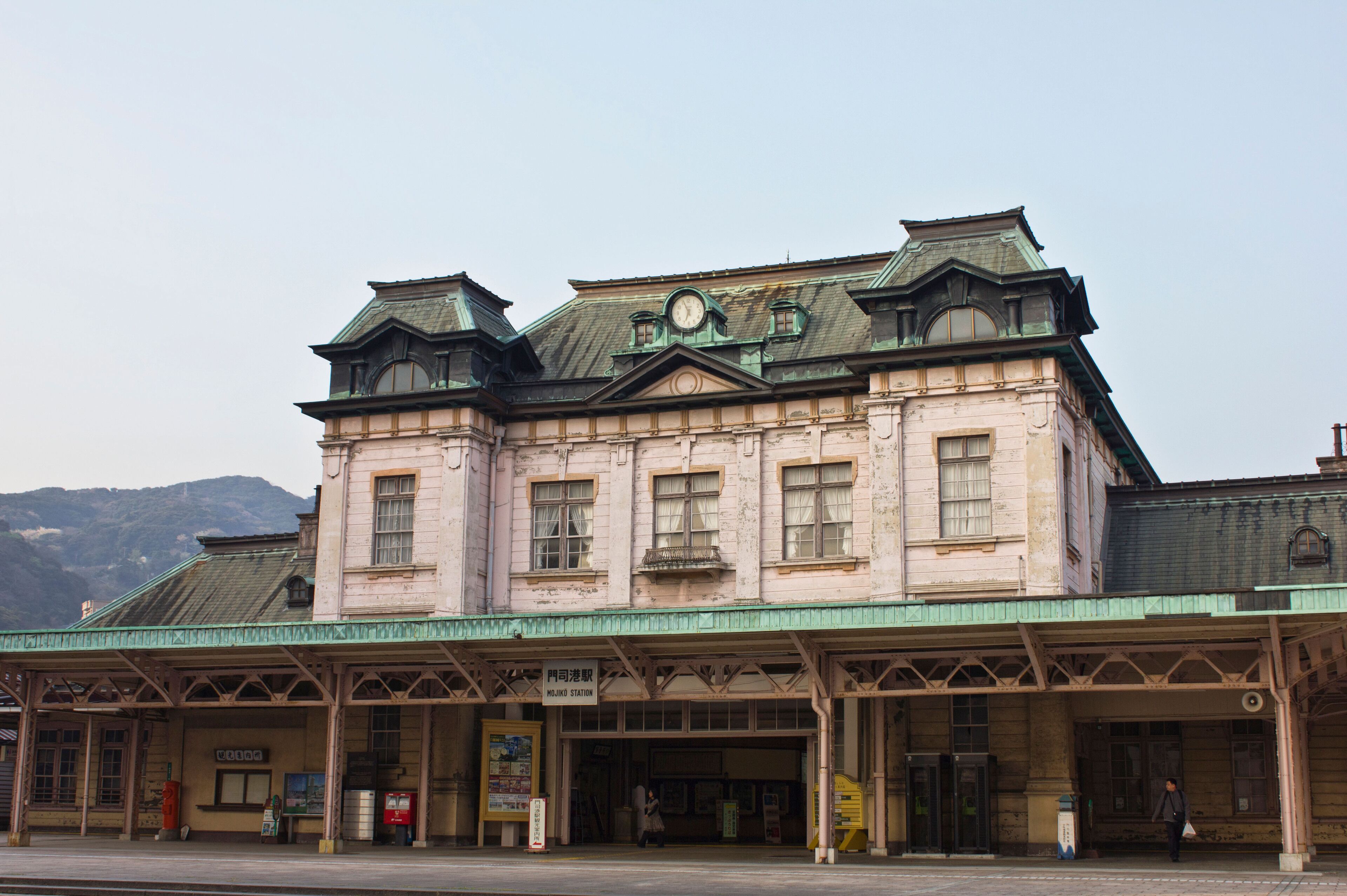 A historic train station with a green roof and a clock tower.
