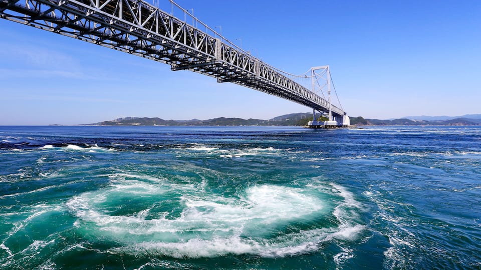 A bridge over a turbulent sea with clear skies.