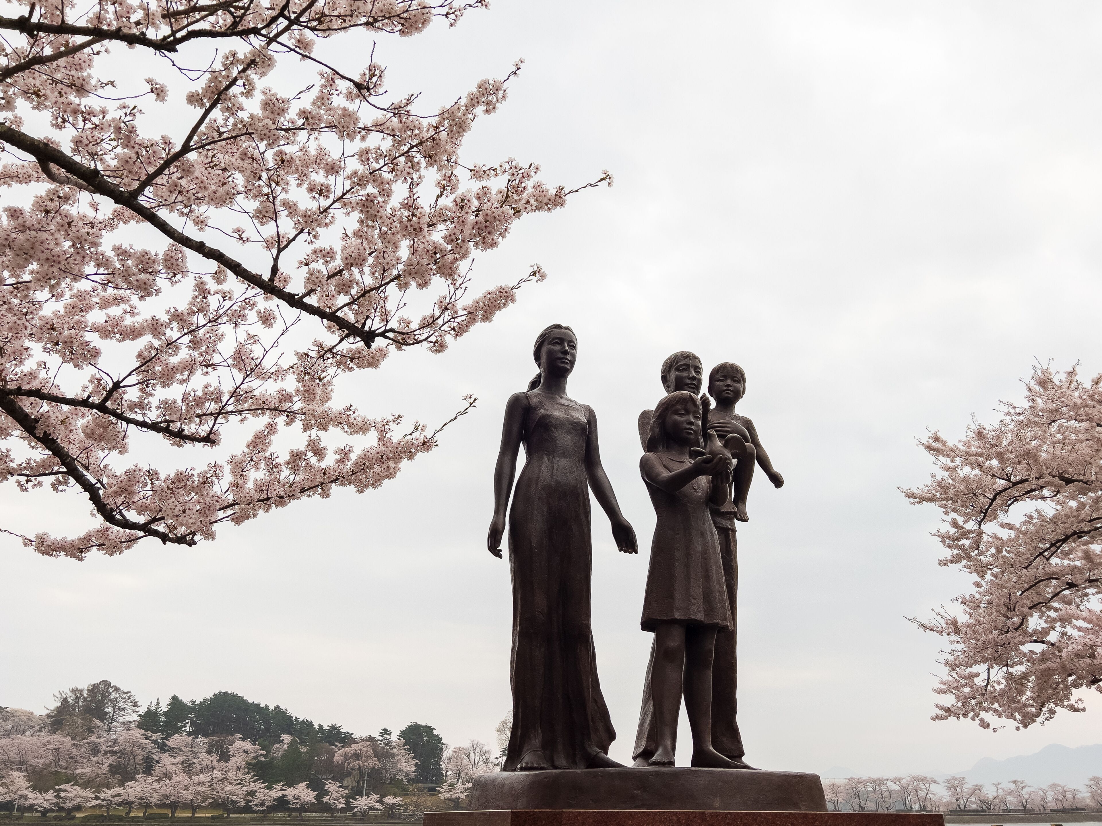 Family statue at Takamatsu Park surrounded by cherry blossoms (sakura) in spring, Morioka, Japan.