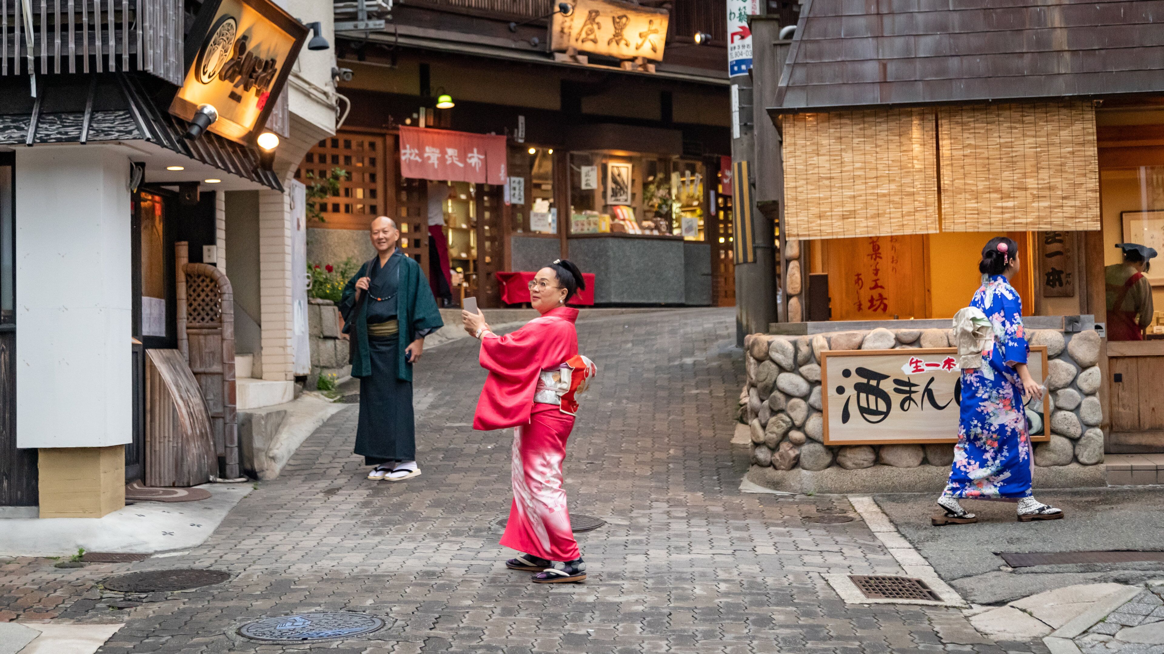 A street with traditional Japanese architecture, including wooden doors and signage with Japanese characters.