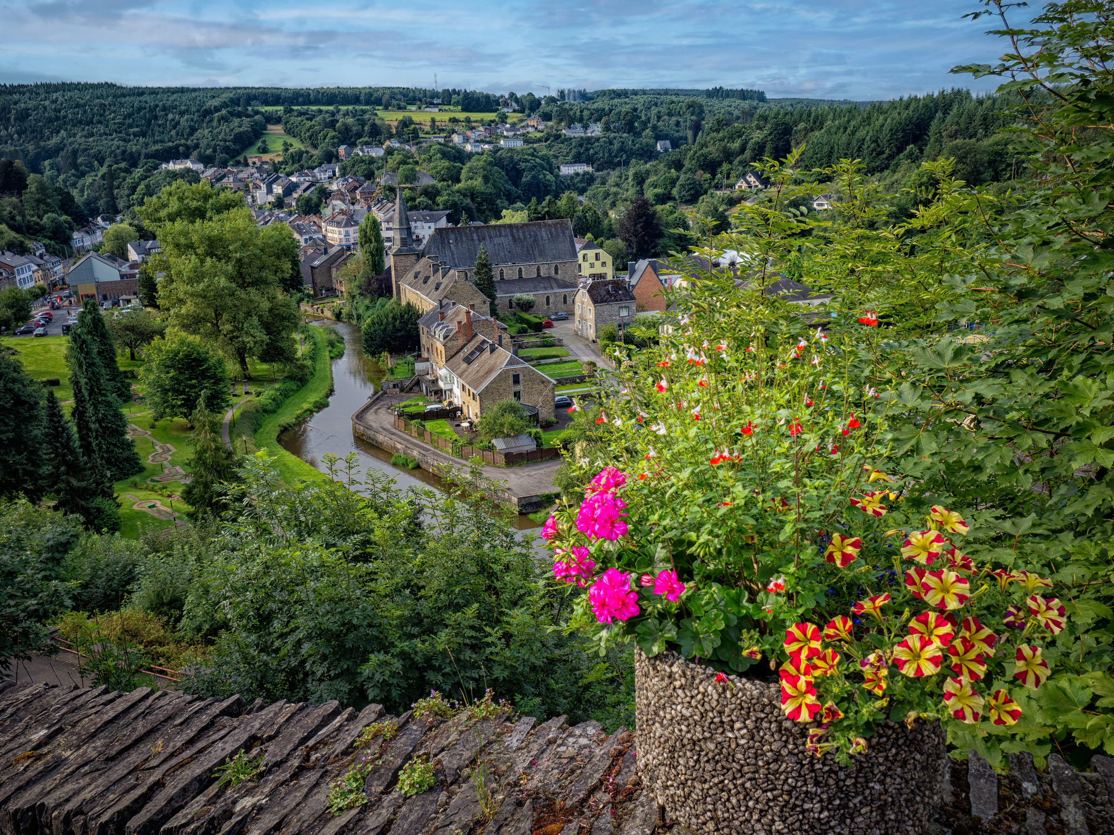 Un village doté de bâtiments historiques, traversé par une rivière et entouré d’une végétation luxuriante.