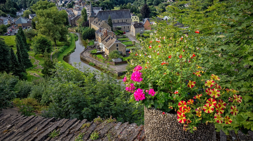 Un village doté de bâtiments historiques, traversé par une rivière et entouré d’une végétation luxuriante.