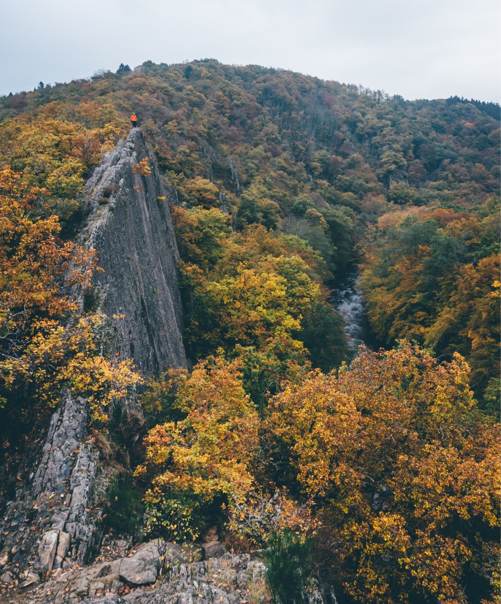 A rocky cliff with a person standing at the top.
