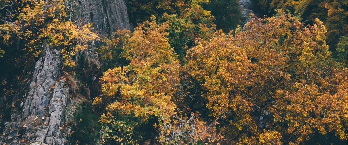 A rocky cliff with a person standing at the top.