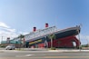 A large ship with the text "Ripley's Believe It or Not!" on its side, parked in front of a building with a green roof.