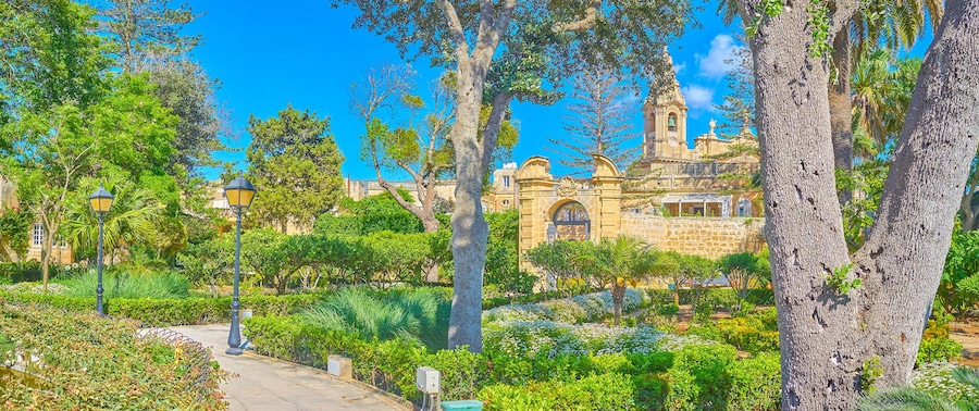 NAXXAR, MALTA - JUNE 14, 2018: The picturesque Italian gardens of Palazzo Parisio, also famous as Scicluna Palace, with shady green trees, flower beds and fountains, on June 14 in Naxxar.