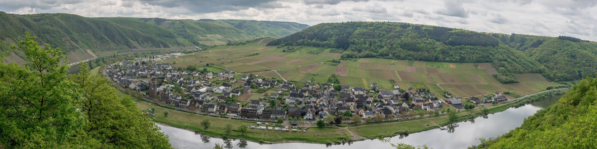 Uma cidade aninhada à beira de um lago, rodeada por colinas e campos verdejantes.
