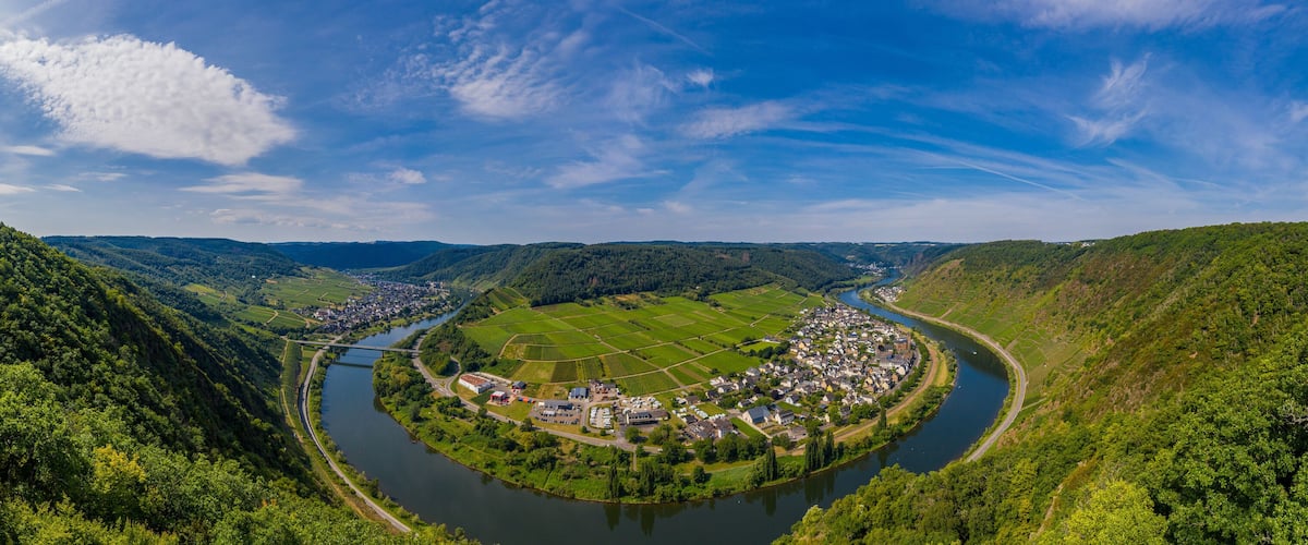A river winding through a valley with a small town and surrounding green hills.