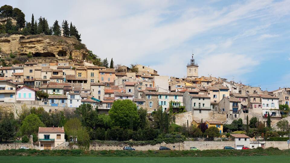 A hillside town with historic buildings, a prominent church, and a rocky hill in the background.