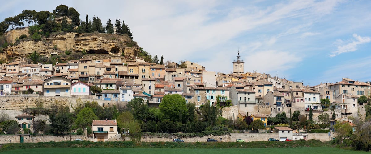 A hillside town with historic buildings, a prominent church, and a rocky hill in the background.