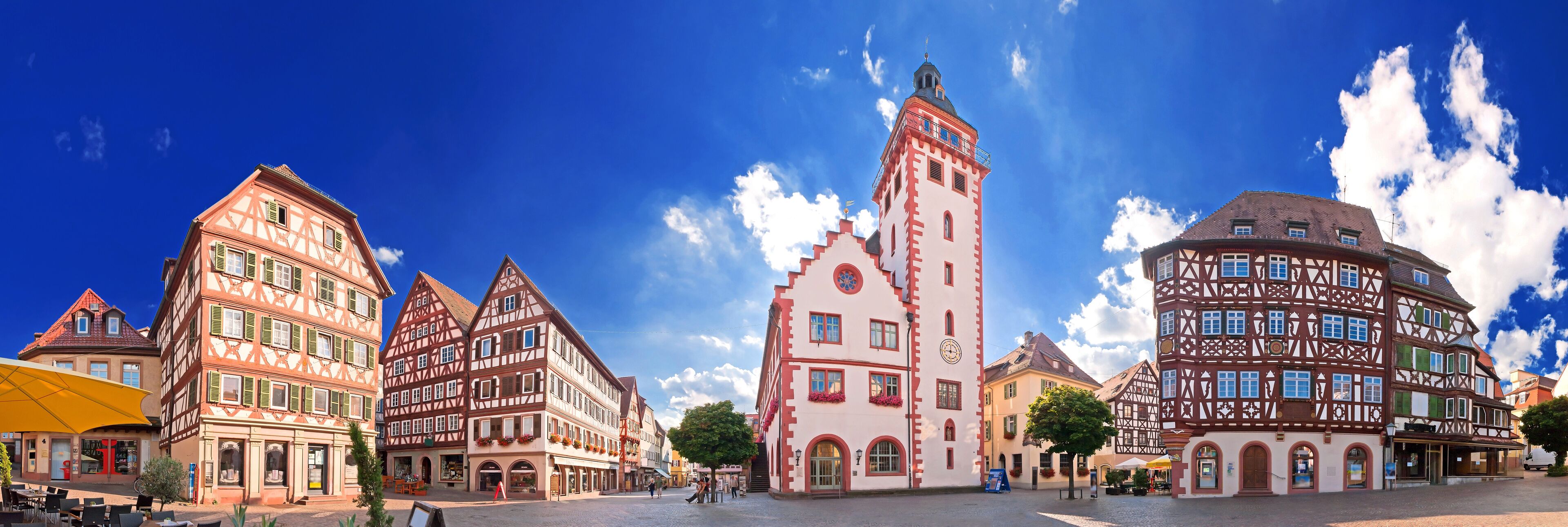 A European town square with traditional half-timbered buildings and a prominent tower.
