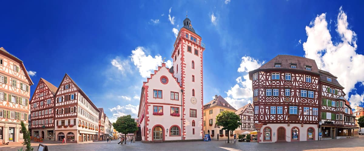 A European town square with traditional half-timbered buildings and a prominent tower.