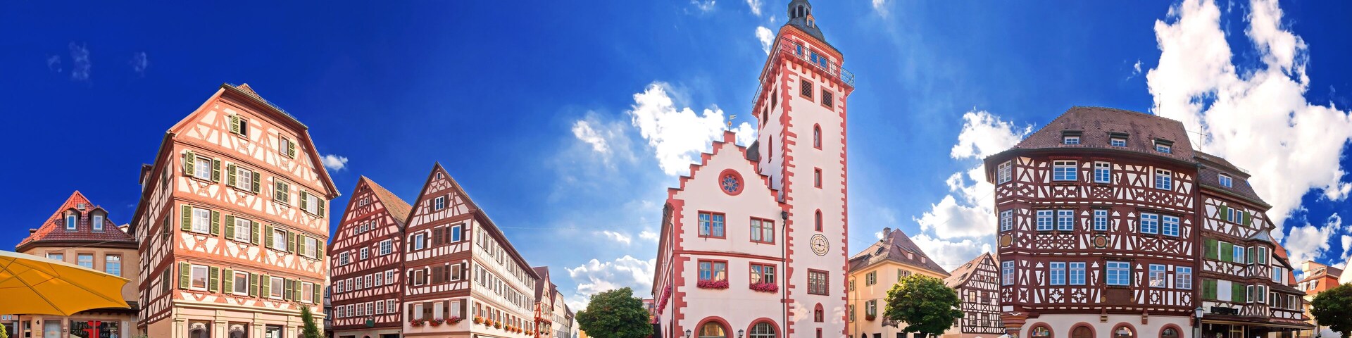 A European town square with traditional half-timbered buildings and a prominent tower.
