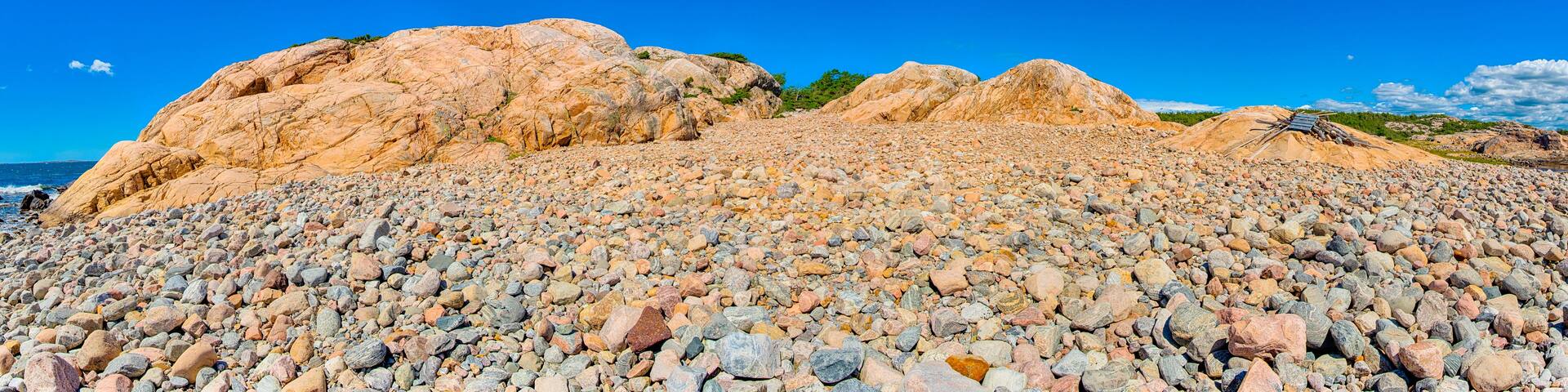A rocky beach with large boulders and a clear blue sky.