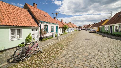GK9510 Two bicycles parked at a cobbled street with small pretty cottages Stora Norregatan, Simrishamn, Skane / Scania, Sweden.
