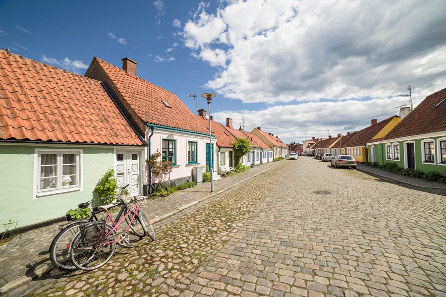 GK9510 Two bicycles parked at a cobbled street with small pretty cottages Stora Norregatan, Simrishamn, Skane / Scania, Sweden.