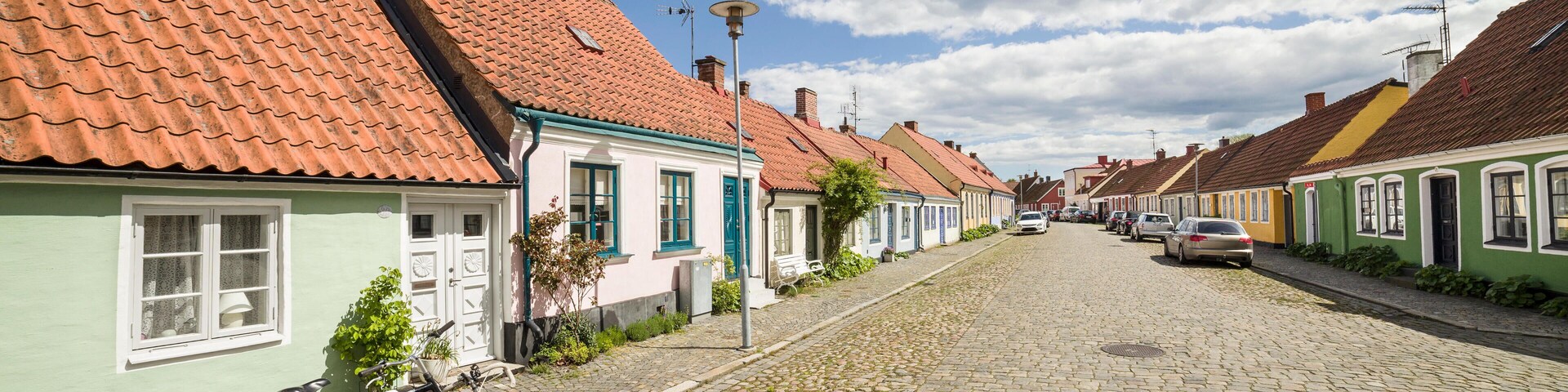 GK9510 Two bicycles parked at a cobbled street with small pretty cottages Stora Norregatan, Simrishamn, Skane / Scania, Sweden.