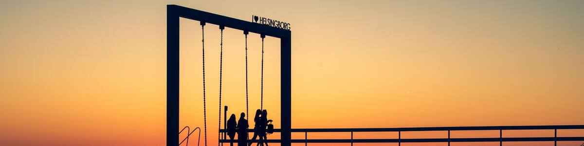 A sunset silhouette of a bridge with people walking on it.