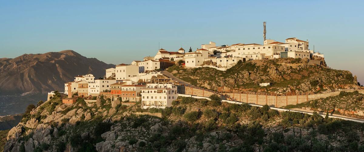 A coastal town built on a rocky hillside with white buildings and a prominent church.