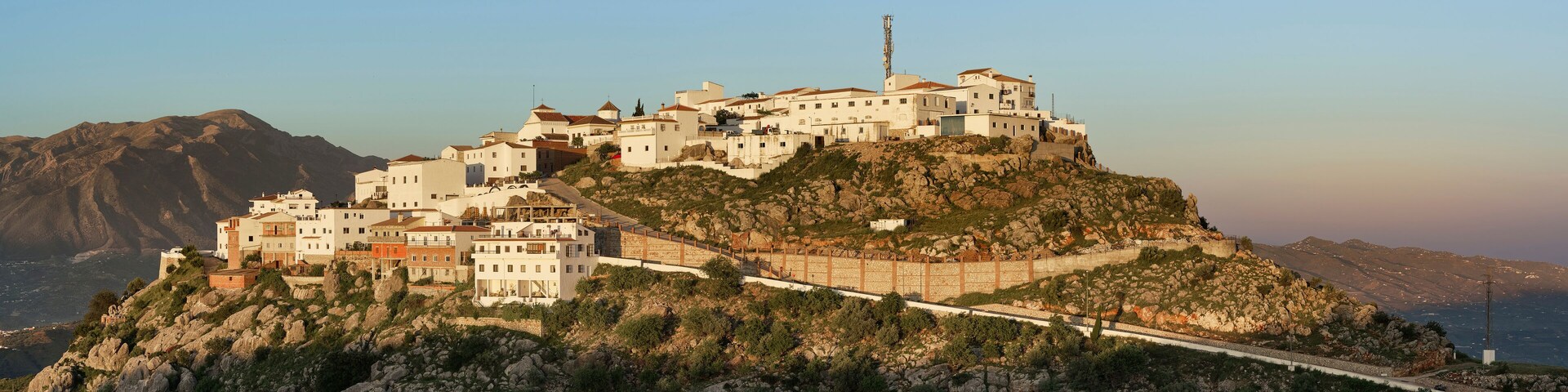 A coastal town built on a rocky hillside with white buildings and a prominent church.
