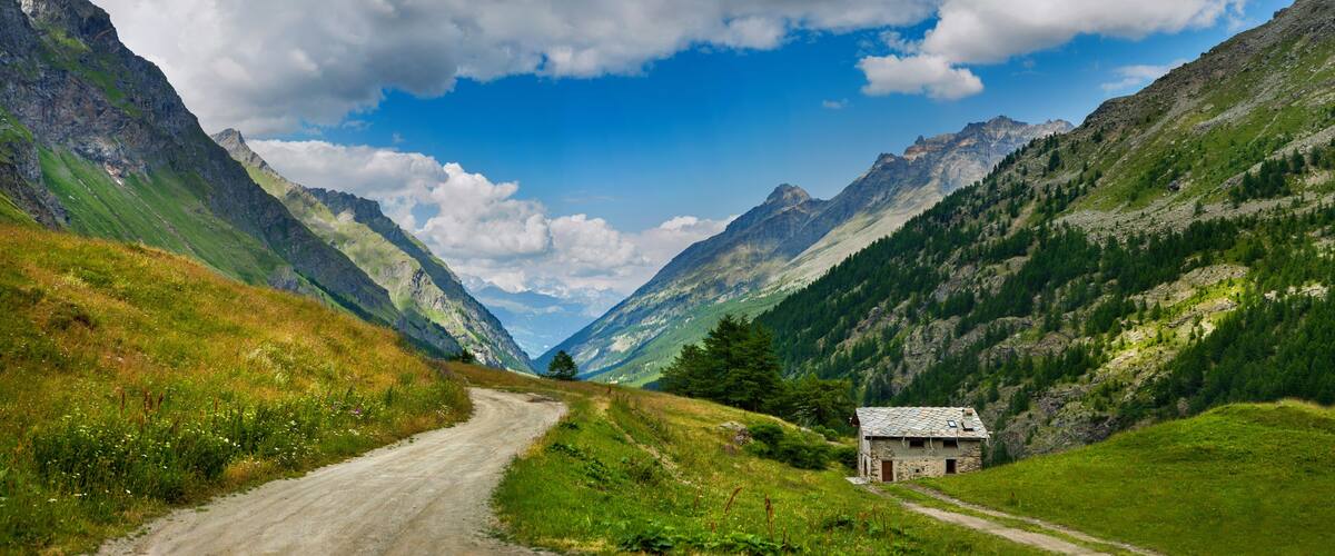 A mountain road with a small stone house on the right.