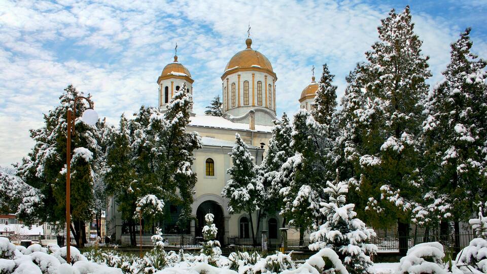 A snow-covered church with domed architecture and a clear sky.