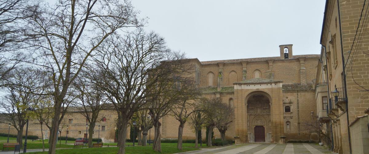 A courtyard with a historic building, trees, and a paved walkway.