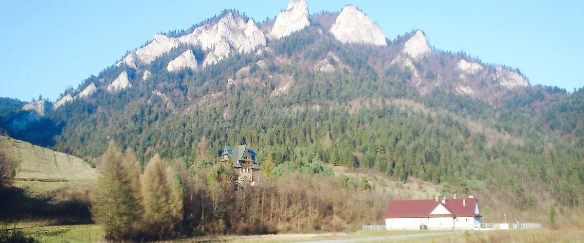 A mountain range with a house and a barn in the foreground.