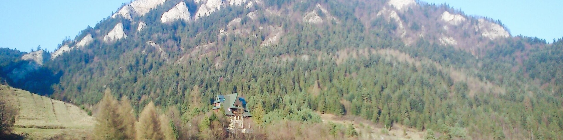 A mountain range with a house and a barn in the foreground.
